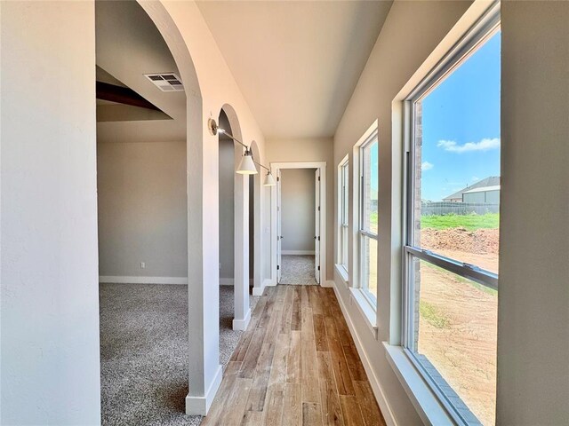 10132 NW 100th St, Yukon, OK 73099 - hallway with healthy amount of natural light, arched walkways, and wood finished floors
