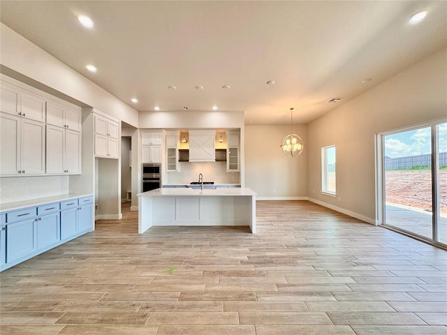 10132 NW 100th St, Yukon, OK 73099 - kitchen featuring white cabinets, light wood-style floors, stainless steel microwave, recessed lighting, and a chandelier