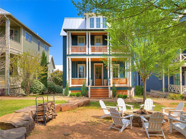 view of front of home featuring metal roof, a balcony, an outdoor fire pit, and covered porch