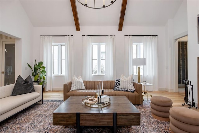 living area featuring lofted ceiling with beams, light wood-style flooring, and baseboards