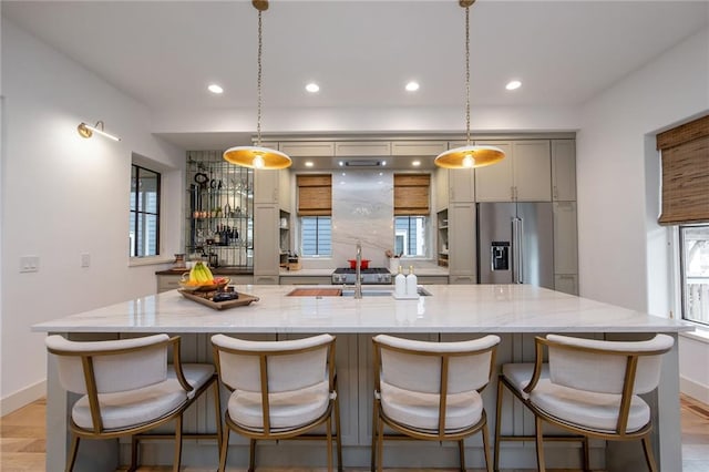 kitchen featuring a large island with sink, baseboards, recessed lighting, and high end fridge