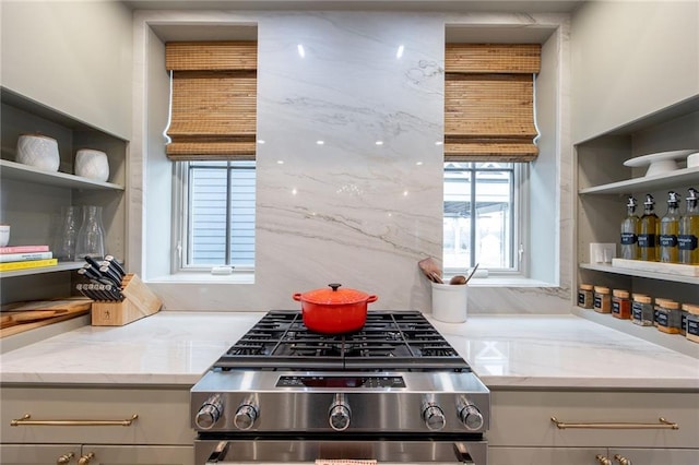 kitchen with open shelves, light stone countertops, and stainless steel gas range oven