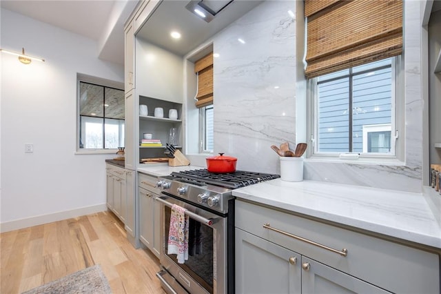 kitchen featuring light wood finished floors, gray cabinets, light stone countertops, baseboards, and stainless steel range