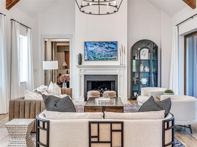 living room with a chandelier, wood finished floors, a healthy amount of sunlight, and high vaulted ceiling