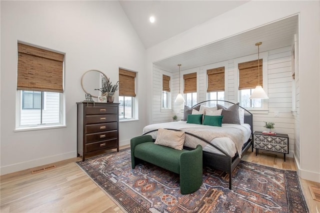 bedroom featuring lofted ceiling, wood finished floors, and multiple windows