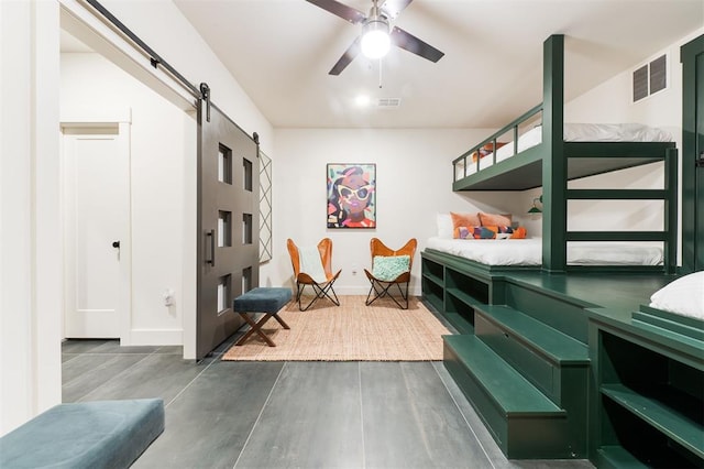 interior space featuring baseboards, wood finished floors, visible vents, and a barn door