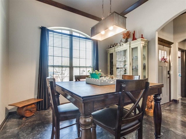 dining space with arched walkways, finished concrete floors, and baseboards