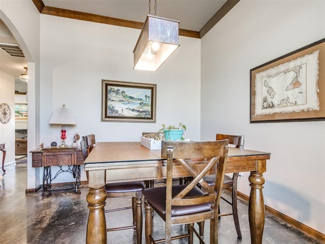 dining area featuring crown molding, arched walkways, concrete floors, visible vents, and baseboards
