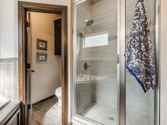 bathroom with toilet, a stall shower, baseboards, and wood tiled floor