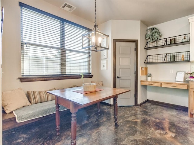 dining room featuring finished concrete flooring, built in desk, a healthy amount of sunlight, and visible vents