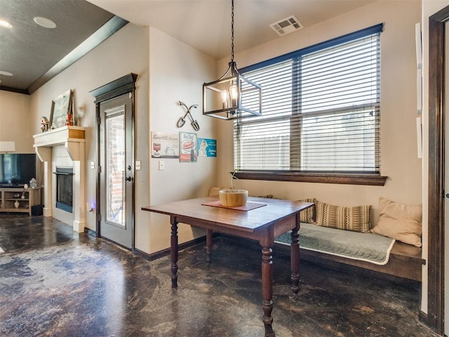 dining room with an inviting chandelier, concrete floors, visible vents, a tile fireplace, and baseboards