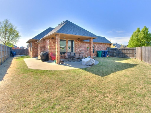 back of house with a patio area, brick siding, a fenced backyard, a yard, and a shingled roof