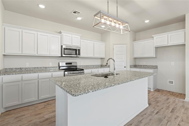 4605 Lincoln Lndg, Harrah, OK 73045 - kitchen featuring appliances with stainless steel finishes, a sink, white cabinetry, a kitchen island with sink, and light wood-style flooring