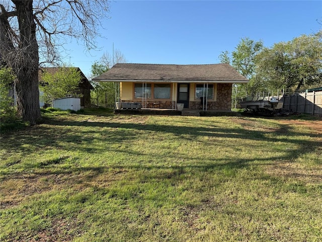 1709 Fisherman Rd, Carnegie, OK 73015 - view of front of house with an outdoor structure, a porch, a storage unit, a front yard, and fence
