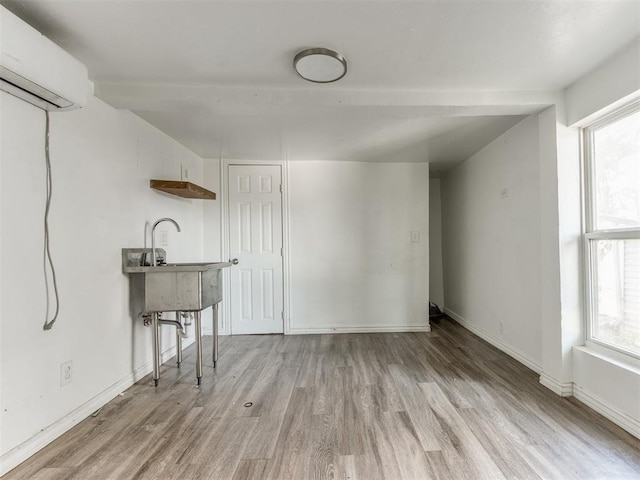 225 NW 24th St, Oklahoma City, OK 73103 - unfurnished living room with a sink, baseboards, wood finished floors, and a wall unit AC