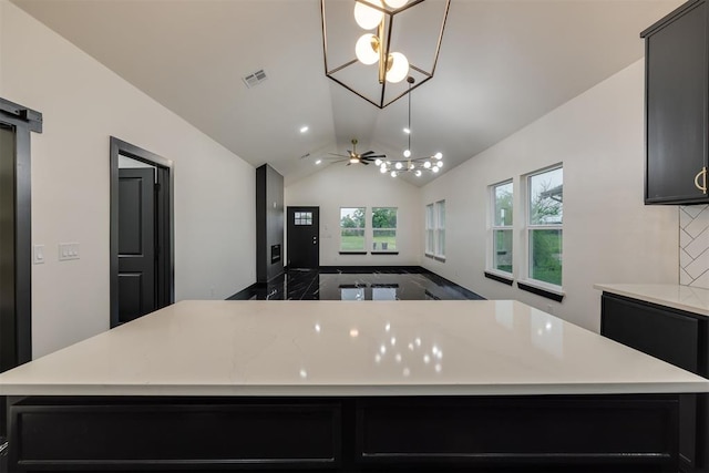 528 NW 112th St, Oklahoma City, OK 73114 - kitchen with a chandelier, light countertops, a center island, vaulted ceiling, and dark cabinetry