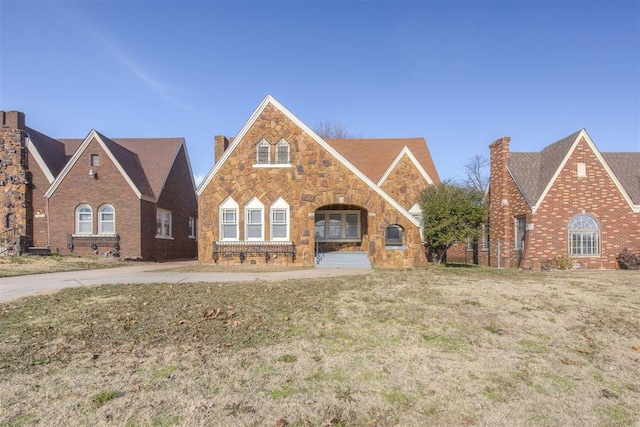 view of front of house featuring a front yard, stone siding, and a chimney