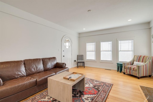 living room with recessed lighting, visible vents, baseboards, and wood finished floors