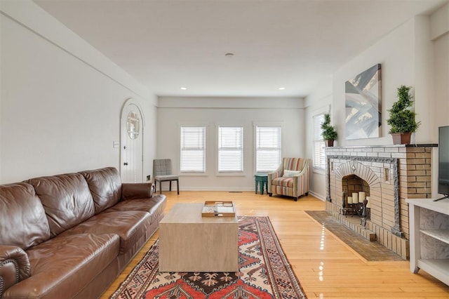 living room with light wood-style flooring, a fireplace, baseboards, and recessed lighting