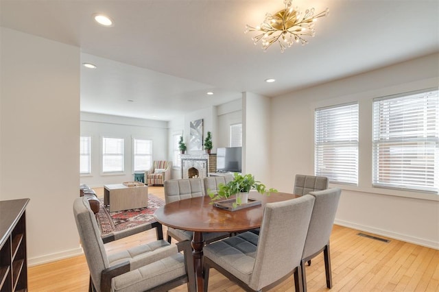 dining area featuring recessed lighting, visible vents, light wood-type flooring, and a brick fireplace