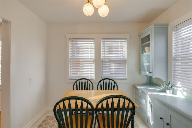 dining space featuring light tile patterned flooring, a notable chandelier, and baseboards