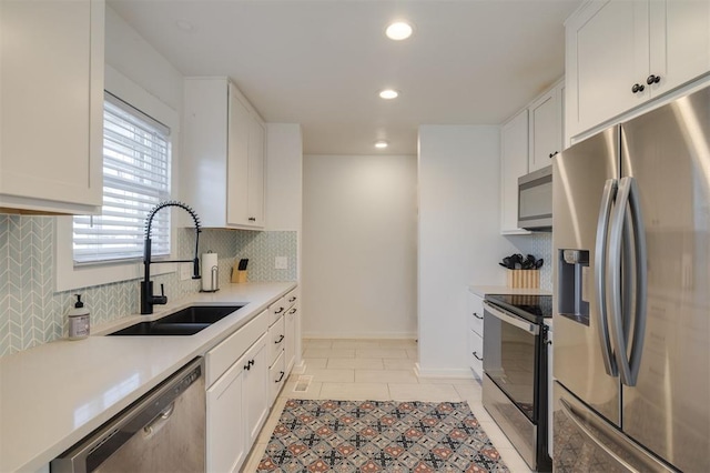 kitchen with stainless steel appliances, white cabinets, a sink, and decorative backsplash
