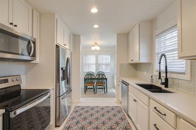kitchen featuring light tile patterned floors, light countertops, backsplash, stainless steel appliances, and a sink