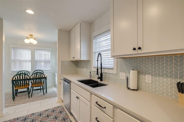 kitchen with tasteful backsplash, light tile patterned floors, white cabinets, dishwasher, and a sink