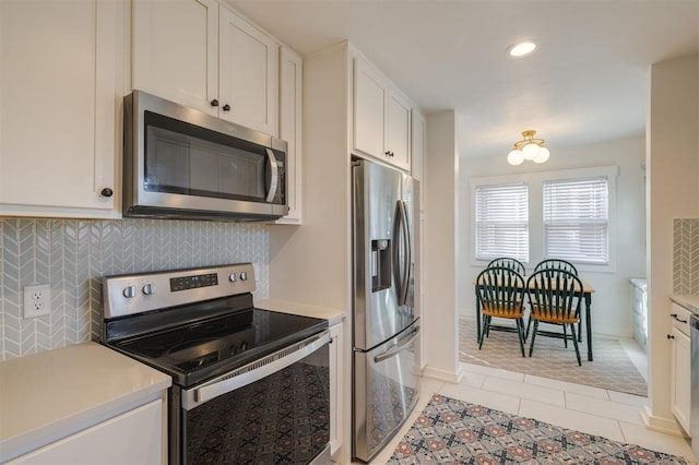 kitchen with light countertops, appliances with stainless steel finishes, white cabinetry, backsplash, and light tile patterned flooring