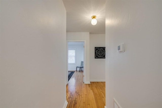 hallway featuring light wood-style flooring and baseboards
