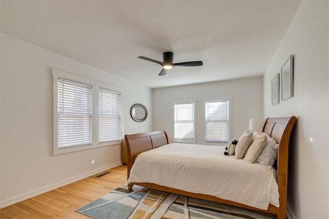 bedroom featuring light wood-style flooring, baseboards, a ceiling fan, and visible vents