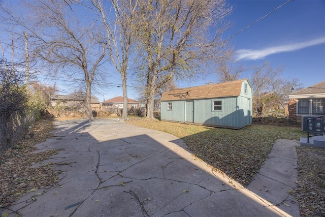 back of house featuring an outdoor structure, a shed, driveway, and roof with shingles
