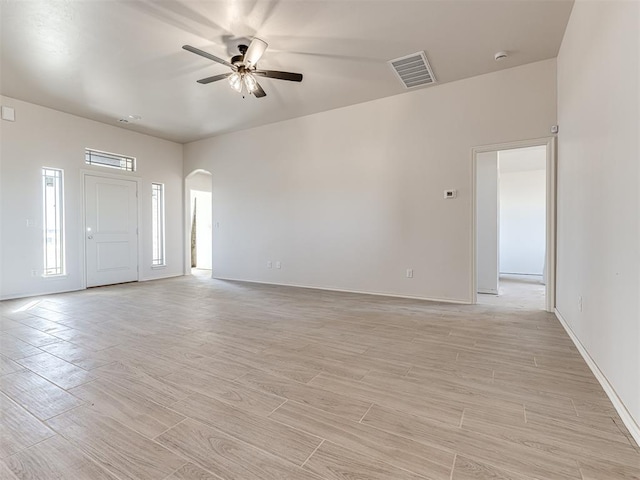 unfurnished living room with visible vents, baseboards, arched walkways, ceiling fan, and wood finish floors