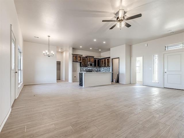 unfurnished living room with visible vents, wood tiled floor, recessed lighting, and ceiling fan with notable chandelier