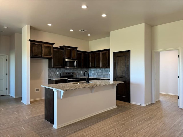 kitchen with light wood-style flooring, visible vents, decorative backsplash, stainless steel appliances, and a sink
