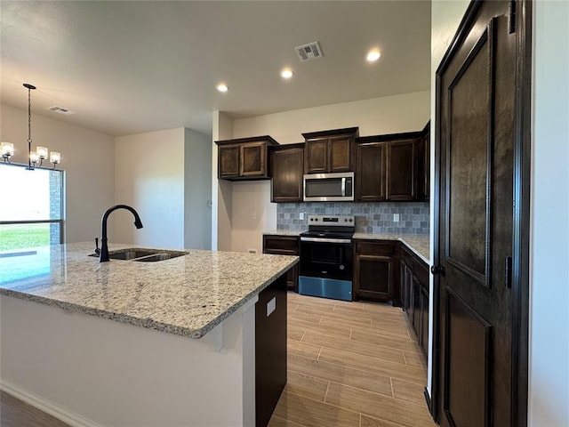 kitchen with a notable chandelier, backsplash, visible vents, appliances with stainless steel finishes, and a sink