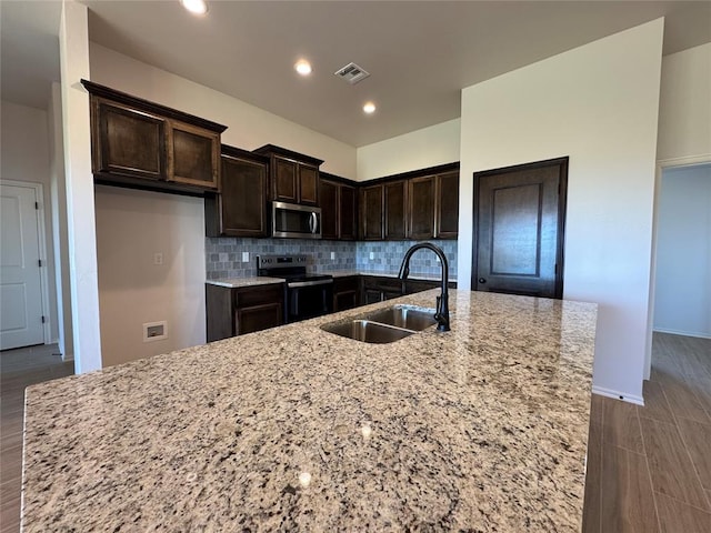 kitchen featuring tasteful backsplash, electric range, visible vents, stainless steel microwave, and a sink