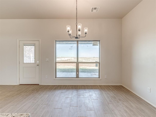 unfurnished dining area featuring visible vents, baseboards, light wood finished floors, and a notable chandelier