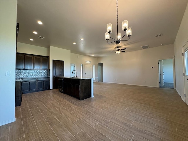 kitchen featuring wood tiled floor, arched walkways, ceiling fan with notable chandelier, and visible vents