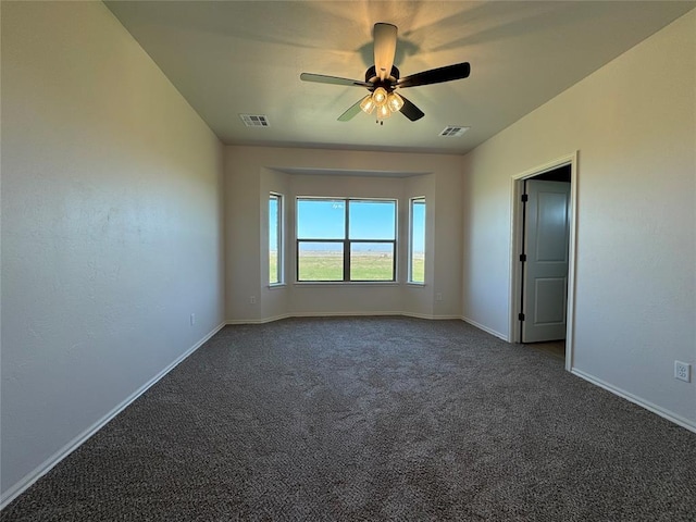 carpeted spare room with visible vents, baseboards, and a ceiling fan