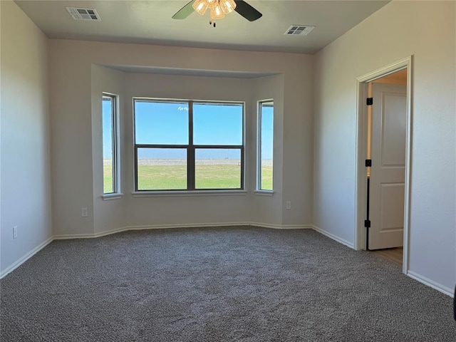 carpeted spare room featuring visible vents, baseboards, and a ceiling fan