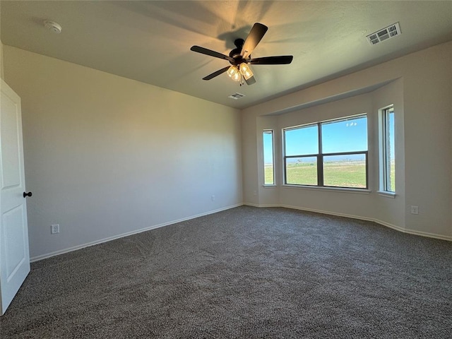spare room featuring visible vents, baseboards, dark carpet, and ceiling fan