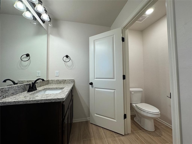 bathroom with toilet, vanity, baseboards, and wood tiled floor