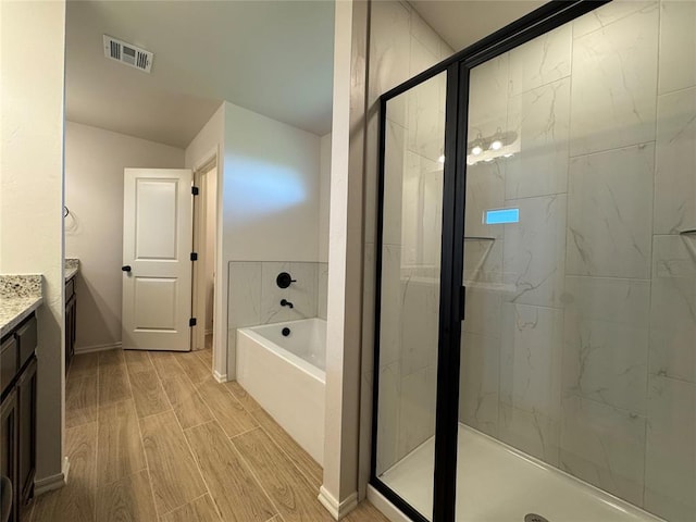 full bathroom with vanity, wood finish floors, a shower stall, visible vents, and a bath