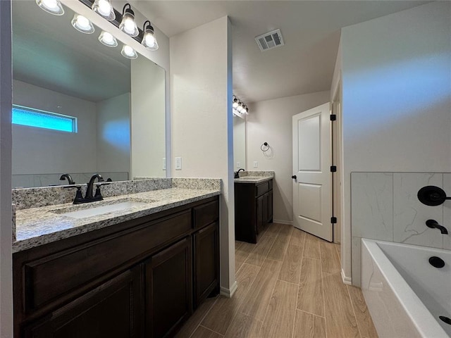 bathroom with two vanities, wood finish floors, a sink, and visible vents
