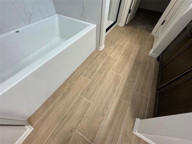 interior space featuring a bath, wood finish floors, and walk in shower