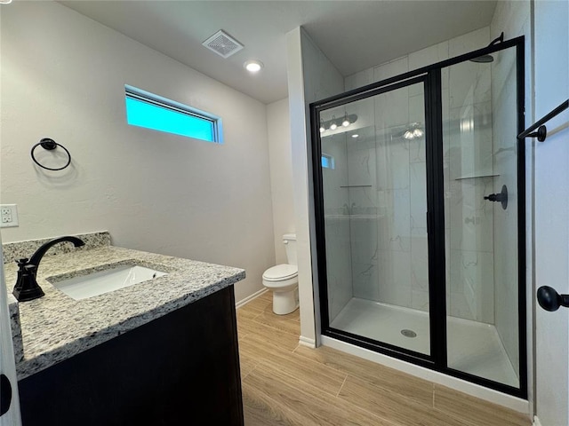 full bath with vanity, toilet, a shower stall, visible vents, and wood finished floors