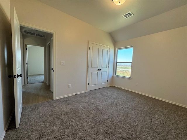 unfurnished bedroom featuring visible vents, baseboards, carpet flooring, and lofted ceiling