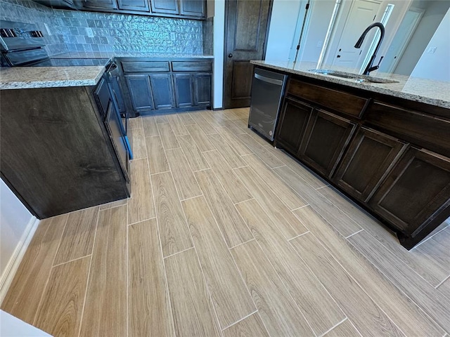 kitchen featuring light stone counters, dishwasher, a sink, wood tiled floor, and decorative backsplash
