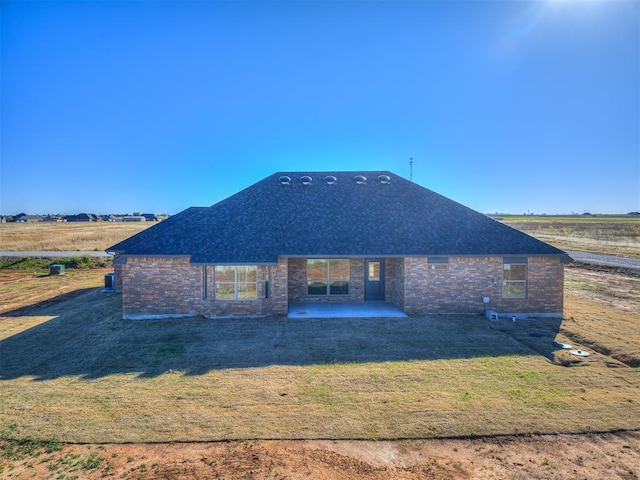 24947 Preakness Run, Cashion, OK 73016 - rear view of house featuring a patio area, a lawn, a shingled roof, and brick siding